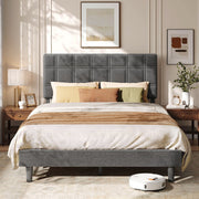 Upholstered double bed with grid-stitched headboard between two wooden bedside tables, robot vacuum below