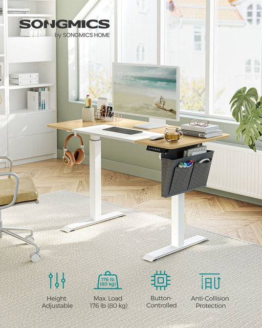 Image of a Songmics Standing Home Office Desk Finished With a Straw Yellow Wooden Tabletop and White Metal Legs and Frame. There is a grey fabric pocket on the side that can be used or books and stationary.