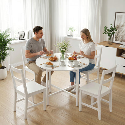 Two people sitting at a round white dining table with food and flowers in a bright room.