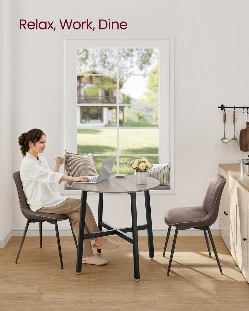 Woman working on a laptop at the Heather Greige round table beside a kitchen window