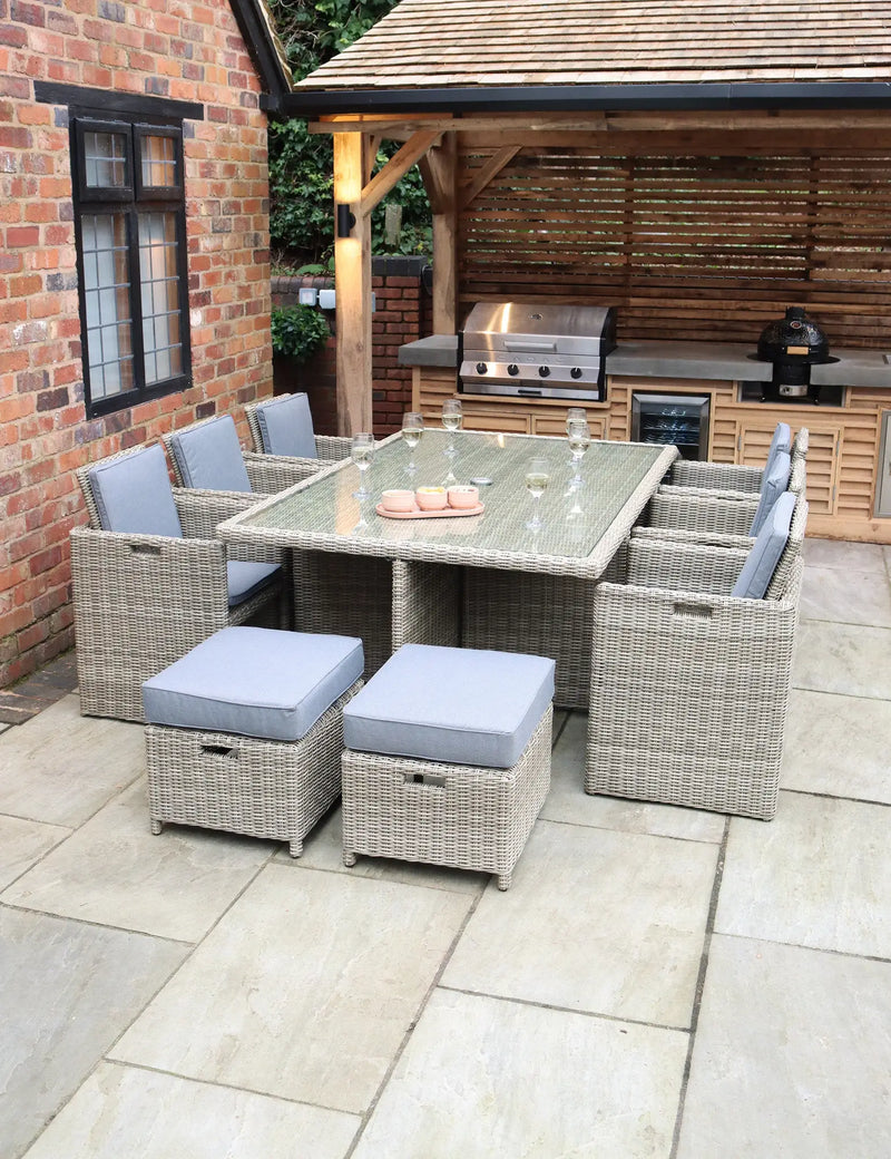 Royalcraft Wentworth rattan cube set with grey cushioned chairs around a glass-top dining table