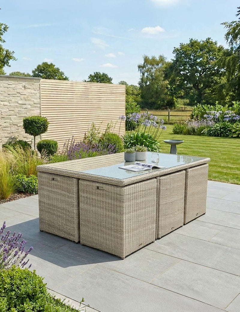 Royalcraft Wentworth rattan cube dining set with glass-top table and cube footstools on a patio