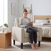 Woman reading a book in the cream accent chair beside a bed