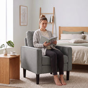 Woman reading a book in the dark grey accent chair beside a bed