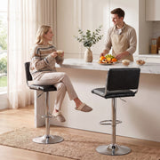 Woman seated on a black bar stool at a white marble kitchen island beside a second stool