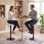 Two people seated on cream white bar stools at a round glass bistro table