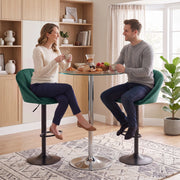 Two people seated on dark green bar stools at a round glass bistro table