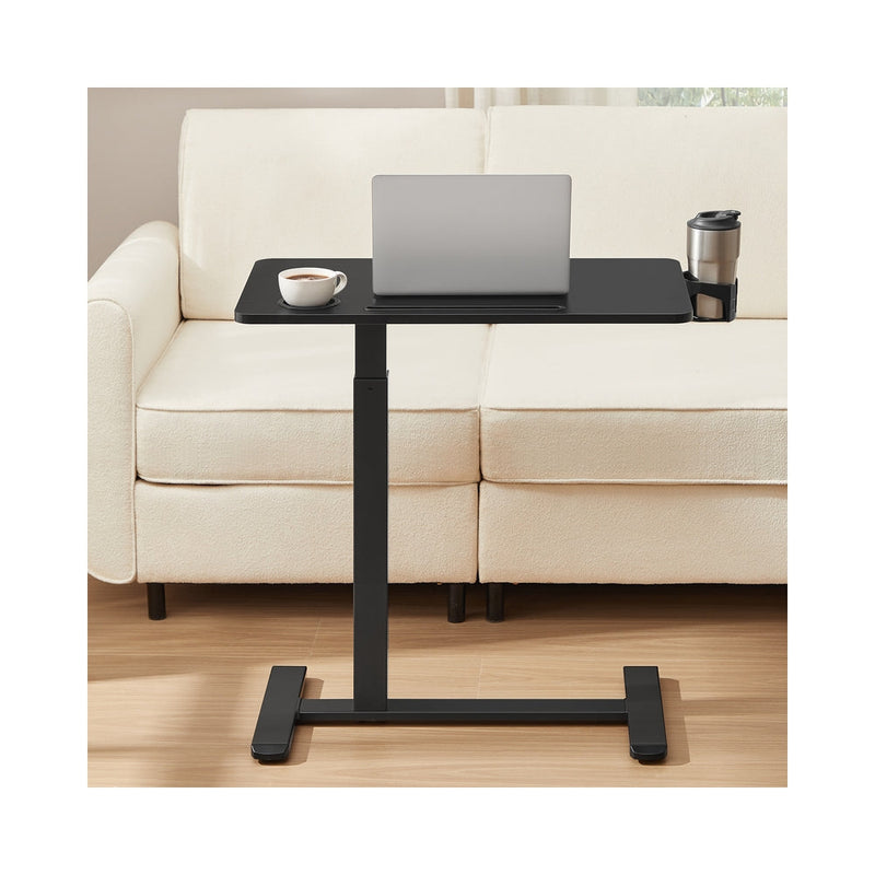 Overbed table positioned over a cream sofa with a laptop, mug and travel cup