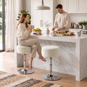 Two beige bar stools at a marble kitchen island with a couple having breakfast