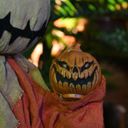 Close-up of the carved pumpkin lantern glowing red in the figure's hand