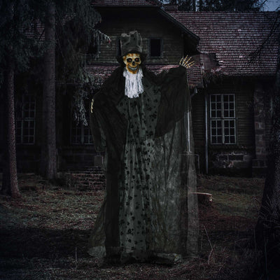 Skeleton reaper decoration lit up at night outside a derelict house