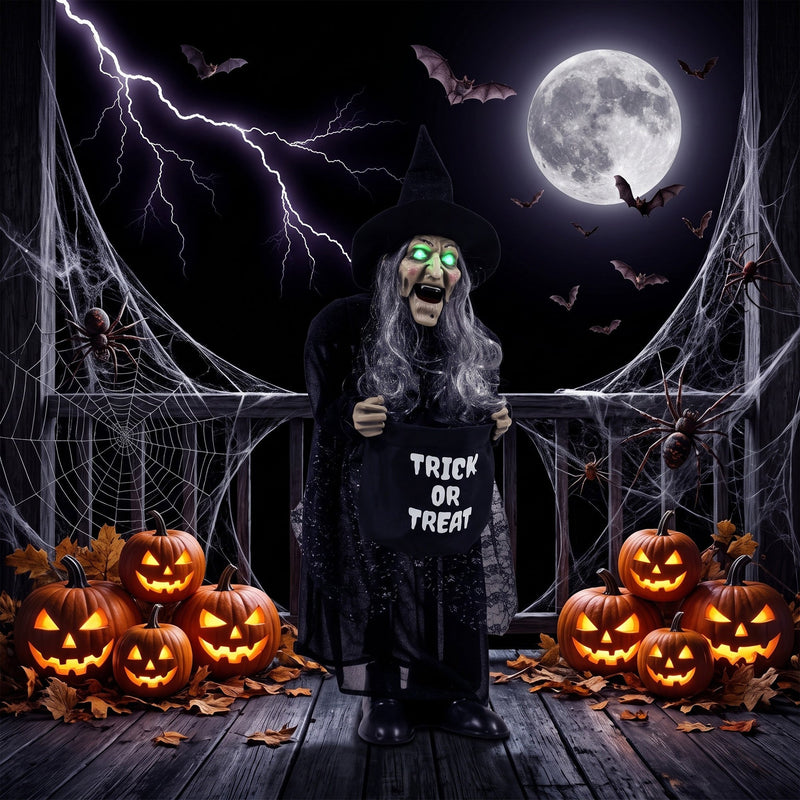 Animated witch decoration with glowing green eyes on a porch surrounded by pumpkins