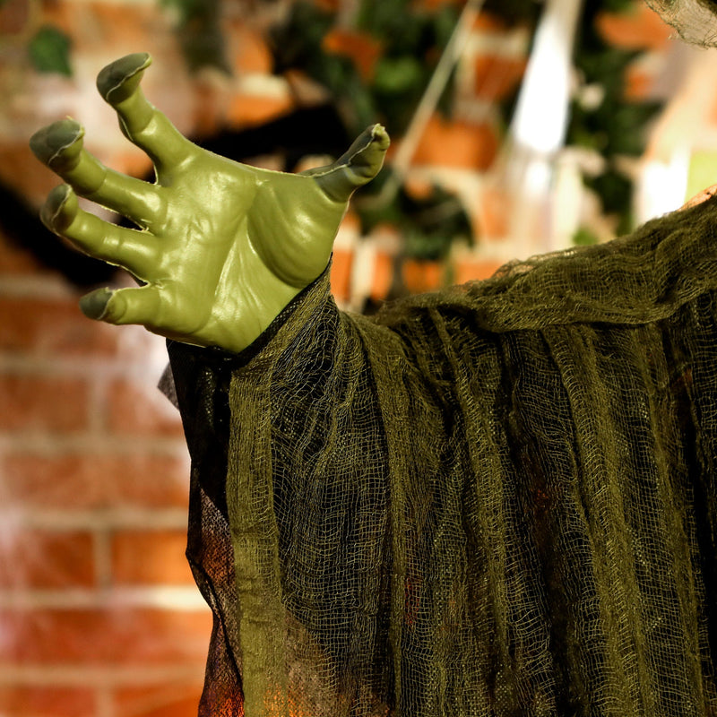 Close-up of the Outsunny Halloween witch's green hand and tattered robe fabric texture