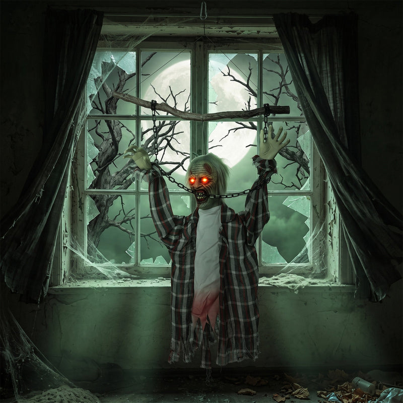 Hanging zombie decoration displayed in front of a broken window with a full moon