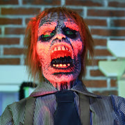Close-up of the zombie's face lit red against a brick wall