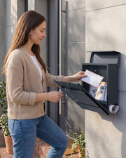 Woman unlocking the mailbox front door with a key to collect letters