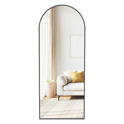 Ink black arched full length mirror on its stand reflecting a living room sofa