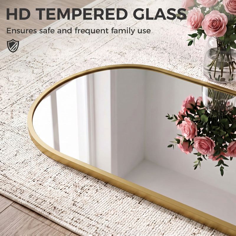 Arched mirror lying on a textured rug with roses, showing the tempered glass and slim frame