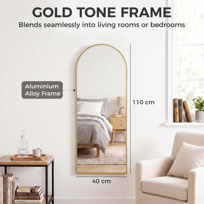 Arched full length mirror in a bedroom setting with frame material label and size markings