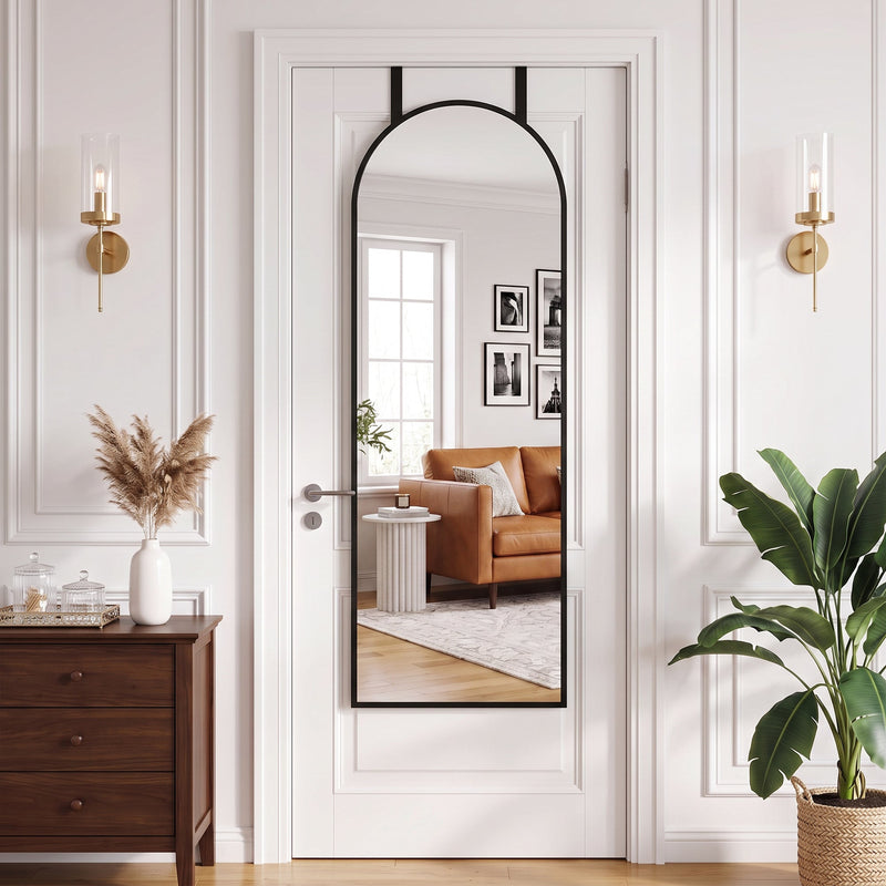 Arched mirror on a panelled door between two wall lights and a chest of drawers
