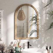 Brown arched mirror mounted above a bathroom sink reflecting a pendant light