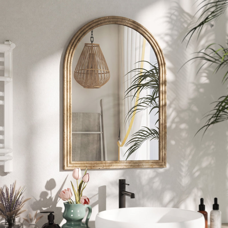 Brown arched mirror mounted above a bathroom sink reflecting a pendant light