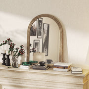 Brown mirror displayed on a mantelpiece with candles and books