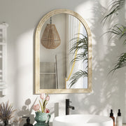 Beige arched mirror mounted above a bathroom sink reflecting a pendant light