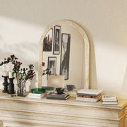 Beige mirror displayed on a mantelpiece with candles and books