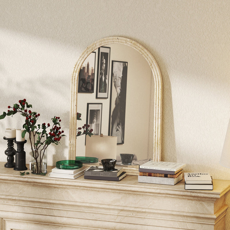 Beige mirror displayed on a mantelpiece with candles and books