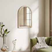 Beige arched mirror mounted above a green sofa in a living room
