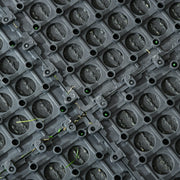 Underside close-up of the tile's snap-connect studs and drainage holes