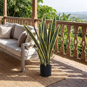 Artificial snake plant on a balcony beside an outdoor sofa