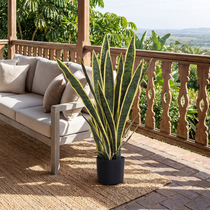 Artificial snake plant on a balcony beside an outdoor sofa