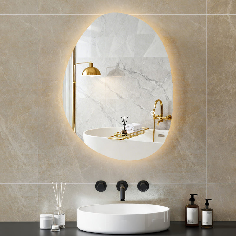 Asymmetric LED bathroom mirror, 70 x 50 cm: warm-lit above a bath in a marble-tiled bathroom