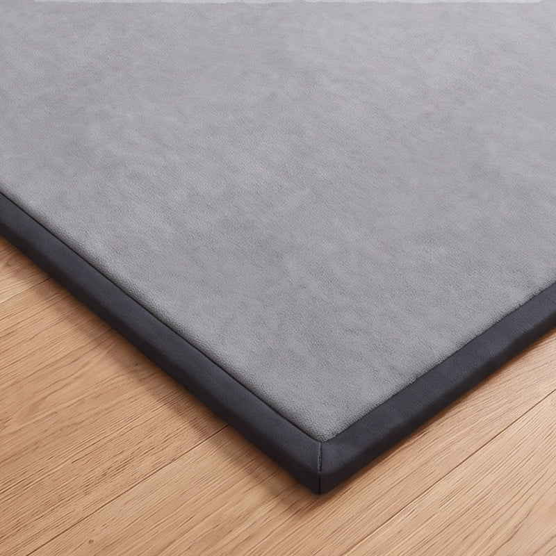 Close-up of the bound corner of the dark grey play mat on a wooden floor