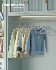 Songmics-branded wardrobe scene with children's sweaters in pastel colours hanging on grey velvet hangers
