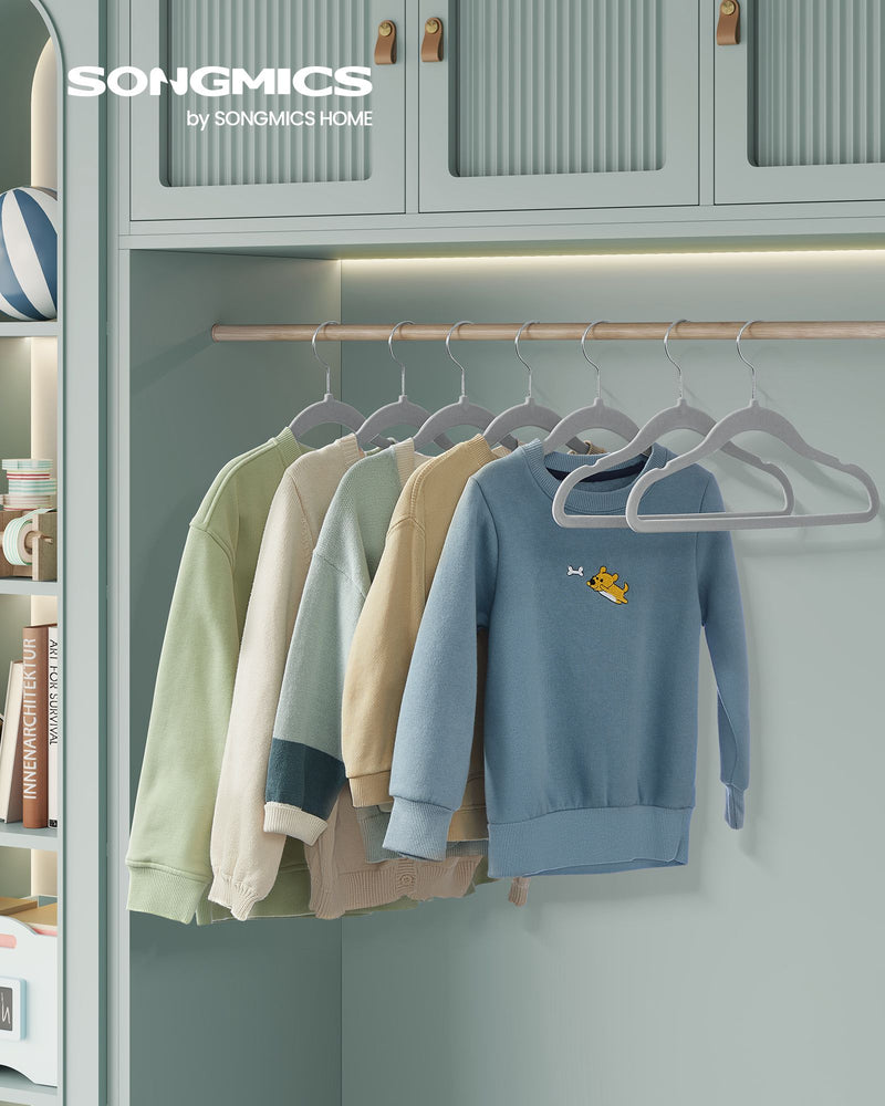 Songmics-branded wardrobe scene with children's sweaters in pastel colours hanging on grey velvet hangers