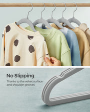 Close-up of children's jumpers on the velvet hangers with a hand touching the fabric, and a 'No Slipping' callout showing the shoulder grooves
