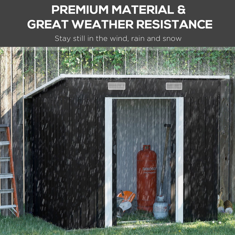 Black 7x4ft metal garden shed standing in heavy rain beside a fence with its sliding doors open