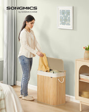 Woman placing clothes into the bamboo laundry basket in a bedroom beside a cabinet