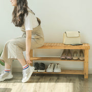 Lifestyle photo of a person sitting on the bamboo bench putting on trainers, with shoes stored on the shelves below