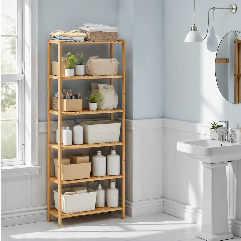 Bamboo shelf in a pale blue bathroom stacked with towels, baskets and bottles beside a basin