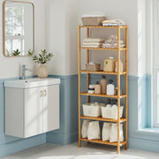 Bamboo shelf in a bathroom corner holding rolled towels, spray bottles and laundry bags