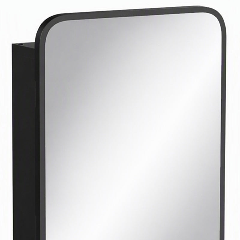 Close-up of the black frame and rounded corner of the mirror cabinet door