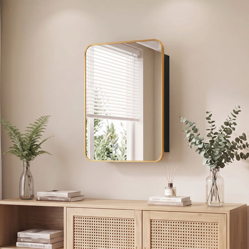 Gold-framed mirror cabinet on a bathroom wall above a rattan sideboard with plants