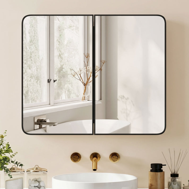Black mirror cabinet above a white basin with gold taps