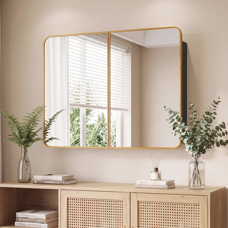 Gold tone mirror cabinet hung above a rattan-front sideboard with plants