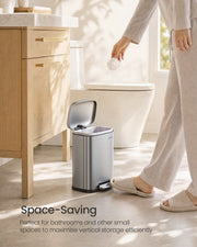 Person stepping on the pedal of the 5 L bin in a bright bathroom, lid open with a liner fitted