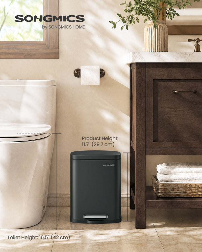Pedal bin with the lid closed beside a toilet and a dark wood vanity unit with folded towels, labelled 29.7 cm product height